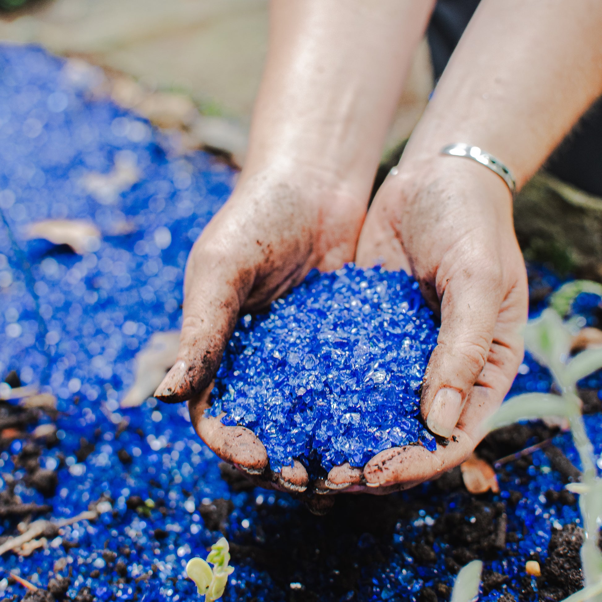 person holding blue recycled glass sand