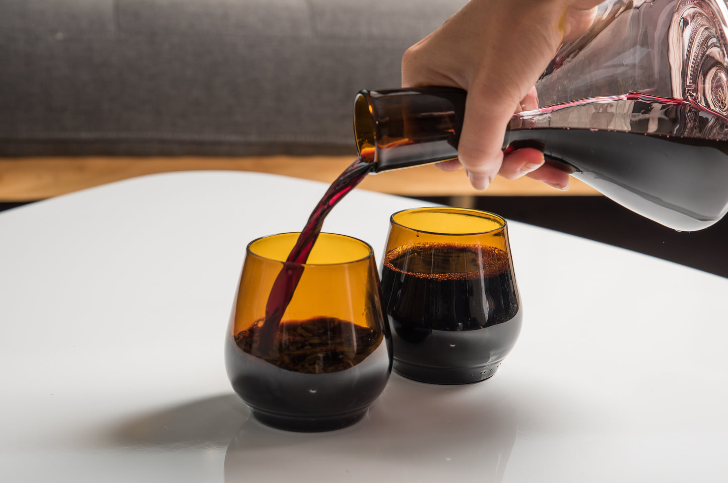 two dark brown short glasses, one of them being poured into