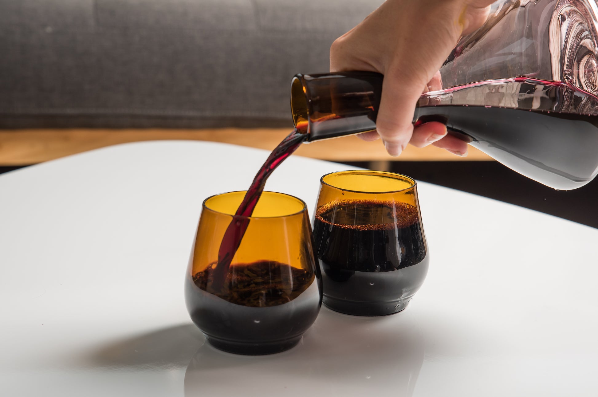 two dark brown short glasses, one of them being poured into