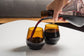 two dark brown short glasses, one of them being poured into