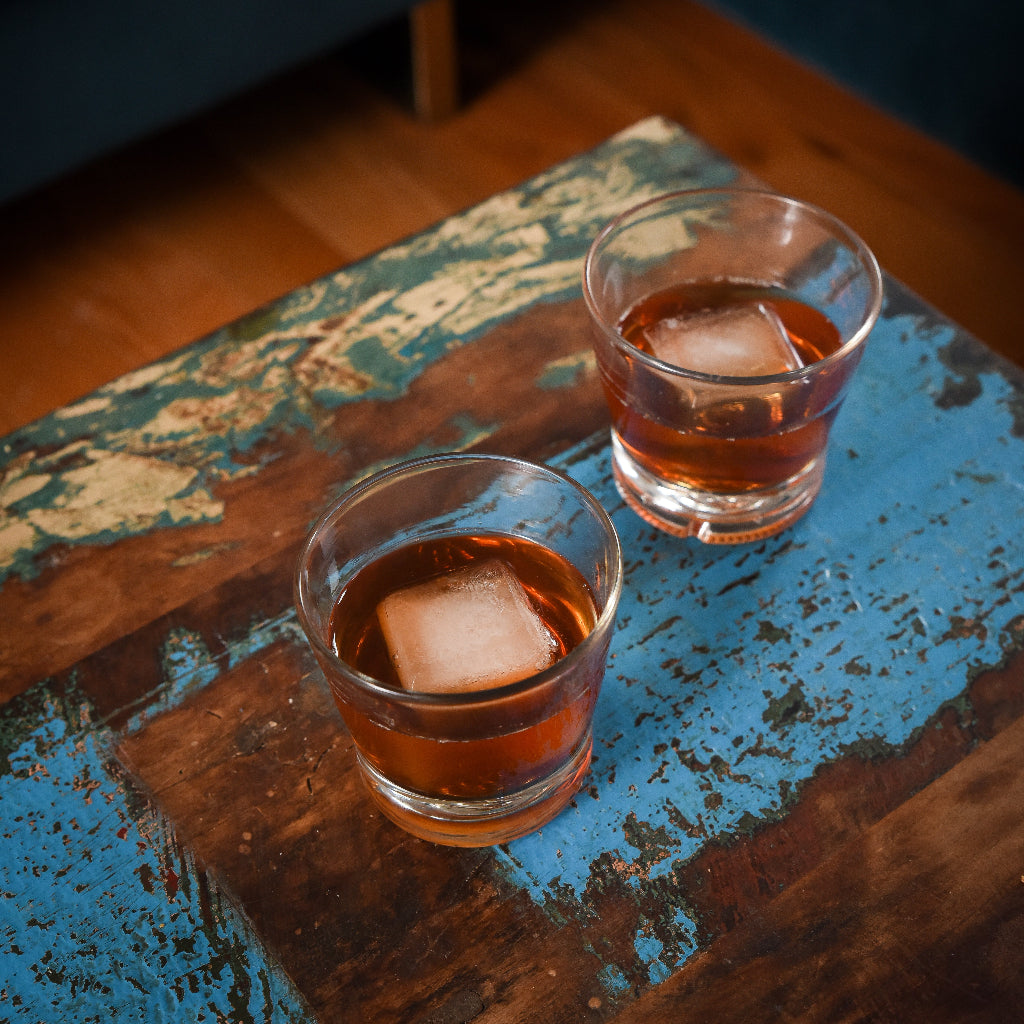 two round rock glasses with ice and drink inside