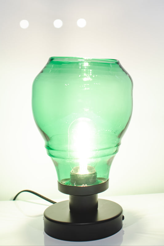 Green glass bottle repurposed as a lamp on a white background