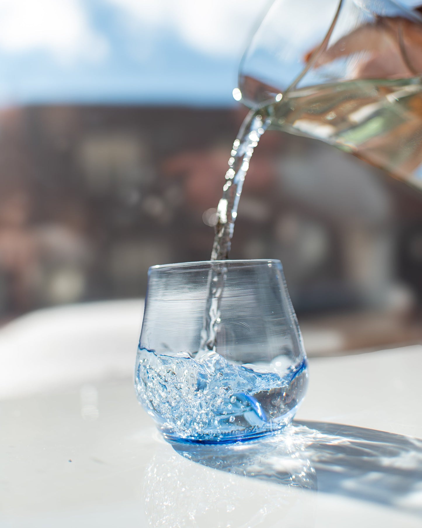 blue short glass being filled with water from pitcher