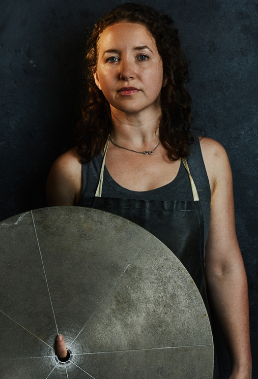 A woman in a grey shirt holding a grey shield 