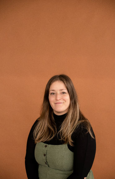 A woman standing in front of a orange background