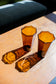 two amber recycled glass water cups with octagon top sitting on wood table with light reflections on table