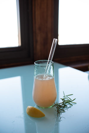 clear straw in champagne flute with strawberry lemonade, rosemary, and fresh lemon slice