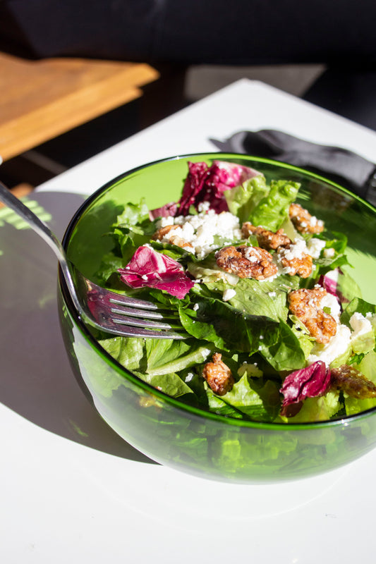 Medium emerald serving bowl made from a recycled bottle. The bowl is full of salad and a person is taking a forkfull.