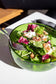 Medium emerald serving bowl made from a recycled bottle. The bowl is full of salad and a person is taking a forkfull.
