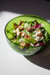 Medium emerald serving bowl made from a recycled bottle. The bowl is full of salad.