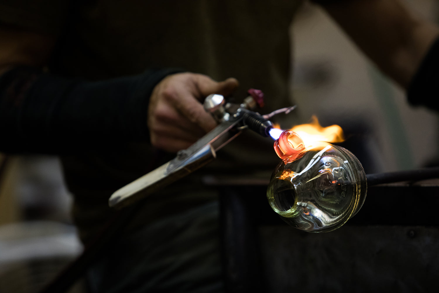 A man holding a torch to heat up clear glass