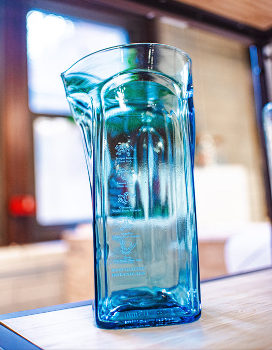 Ice blue glass pitcher in front of a window