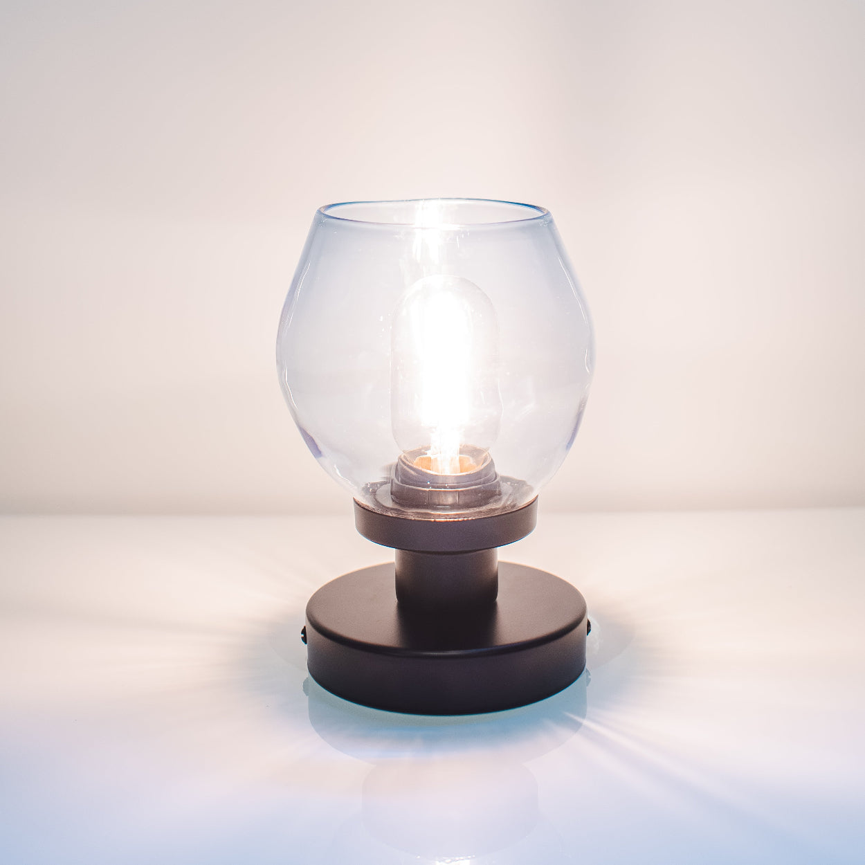 Small glass lamp with black base on a white surface