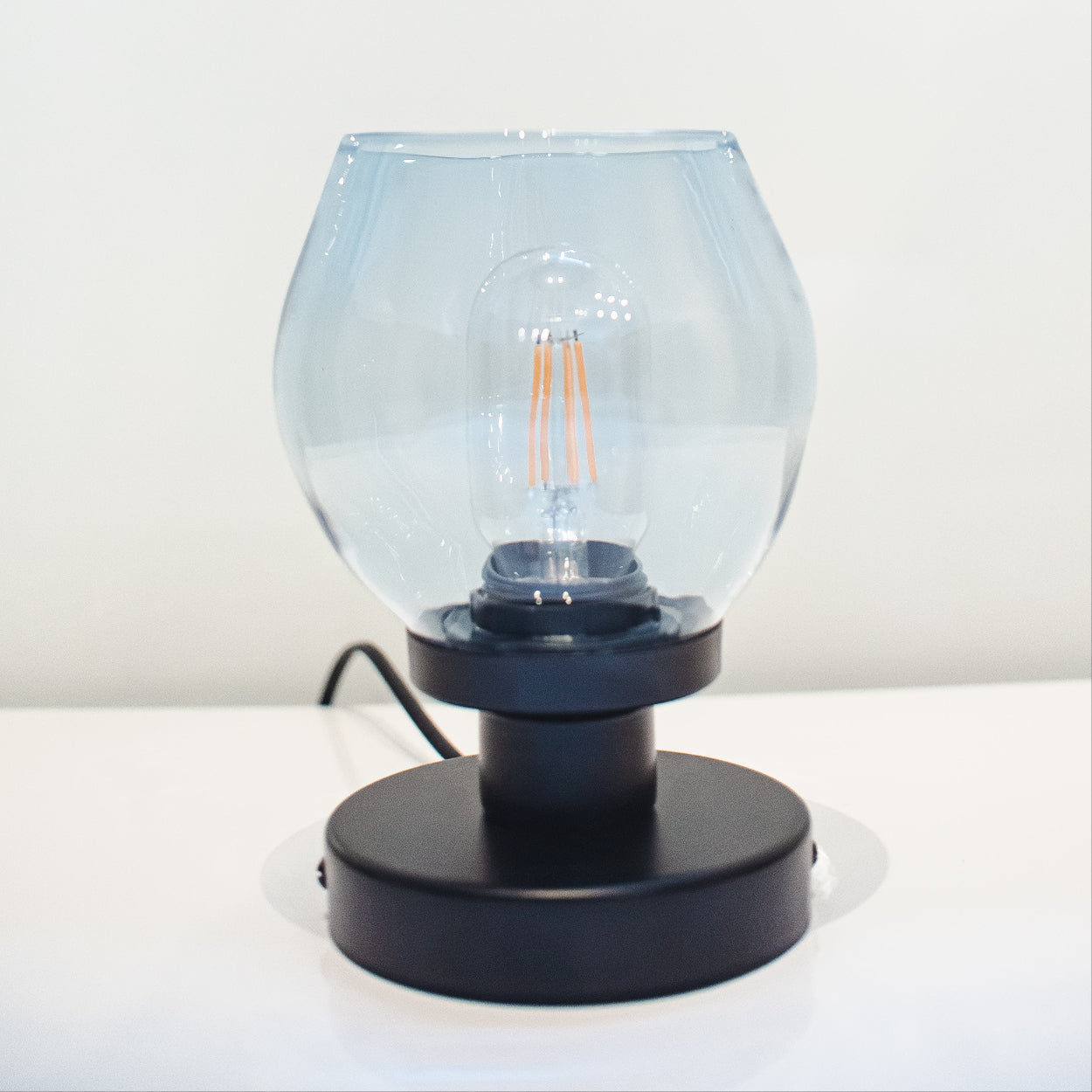 Table lamp with a clear glass shade and black base on a white background