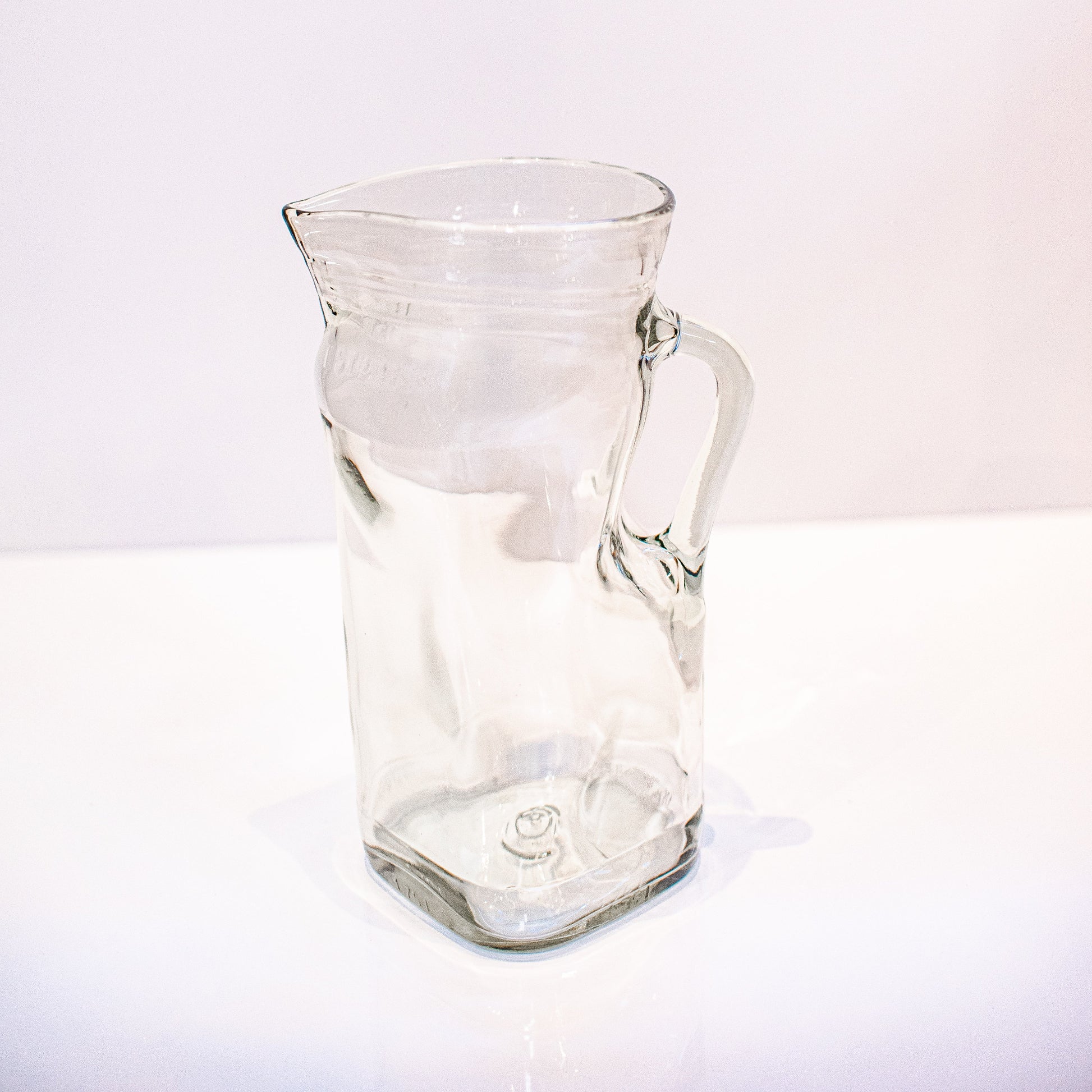 Clear recycled glass pitcher on a white background