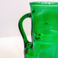 Green glass pitcher on a white background closeup of handle