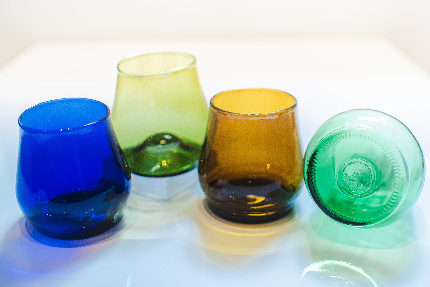 Four colorful glass tumblers on a white surface