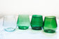 Four green glass tumblers on a white surface