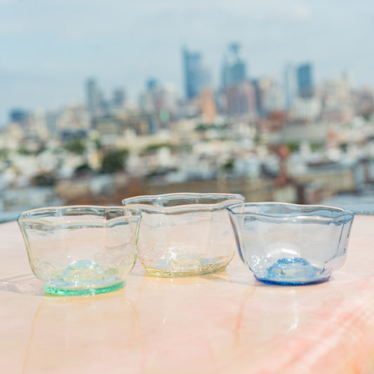 Three glass bowls on a surface with a blurred cityscape in the background