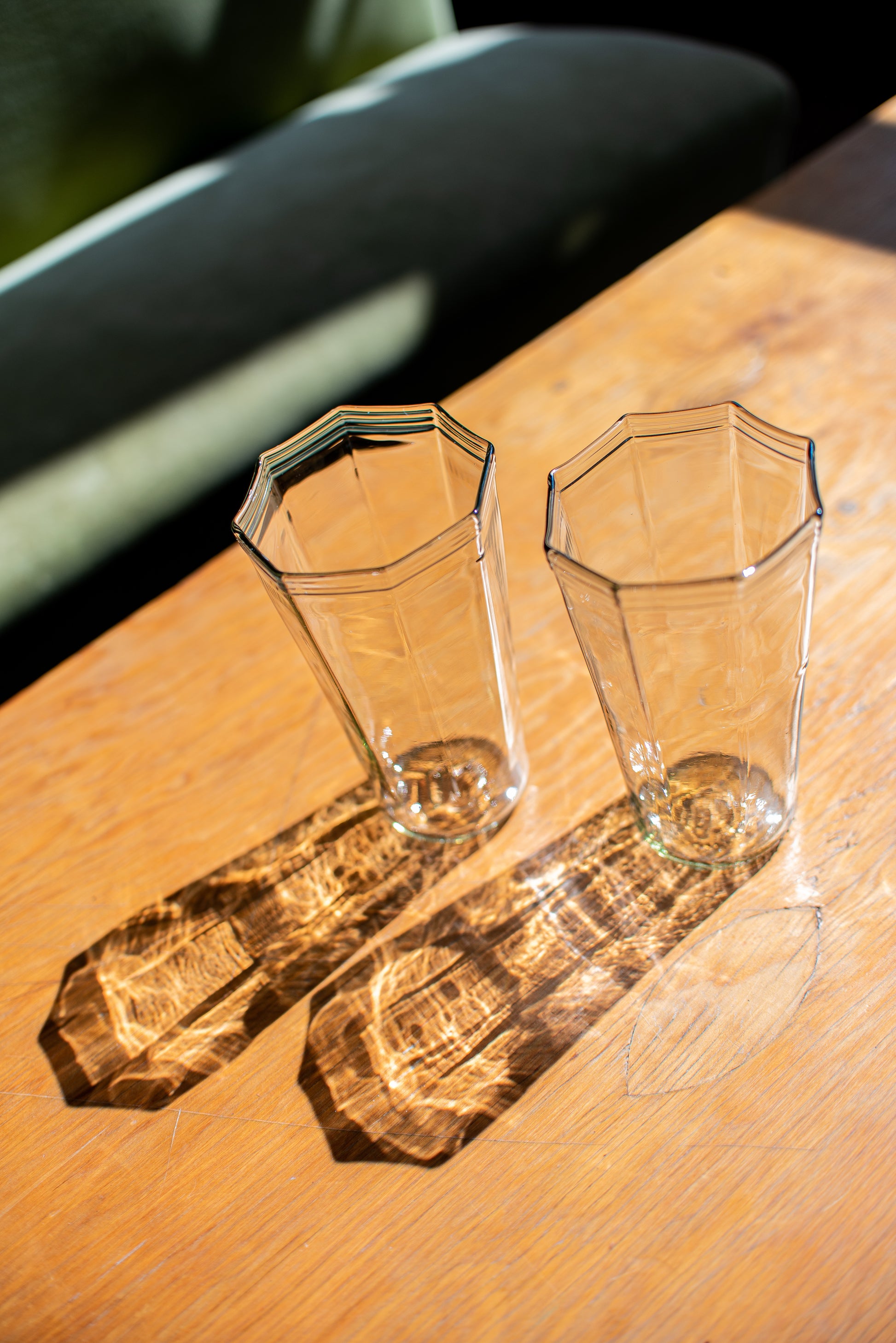 clear recycled glass water glasses with octagon top and reflection onto wood table