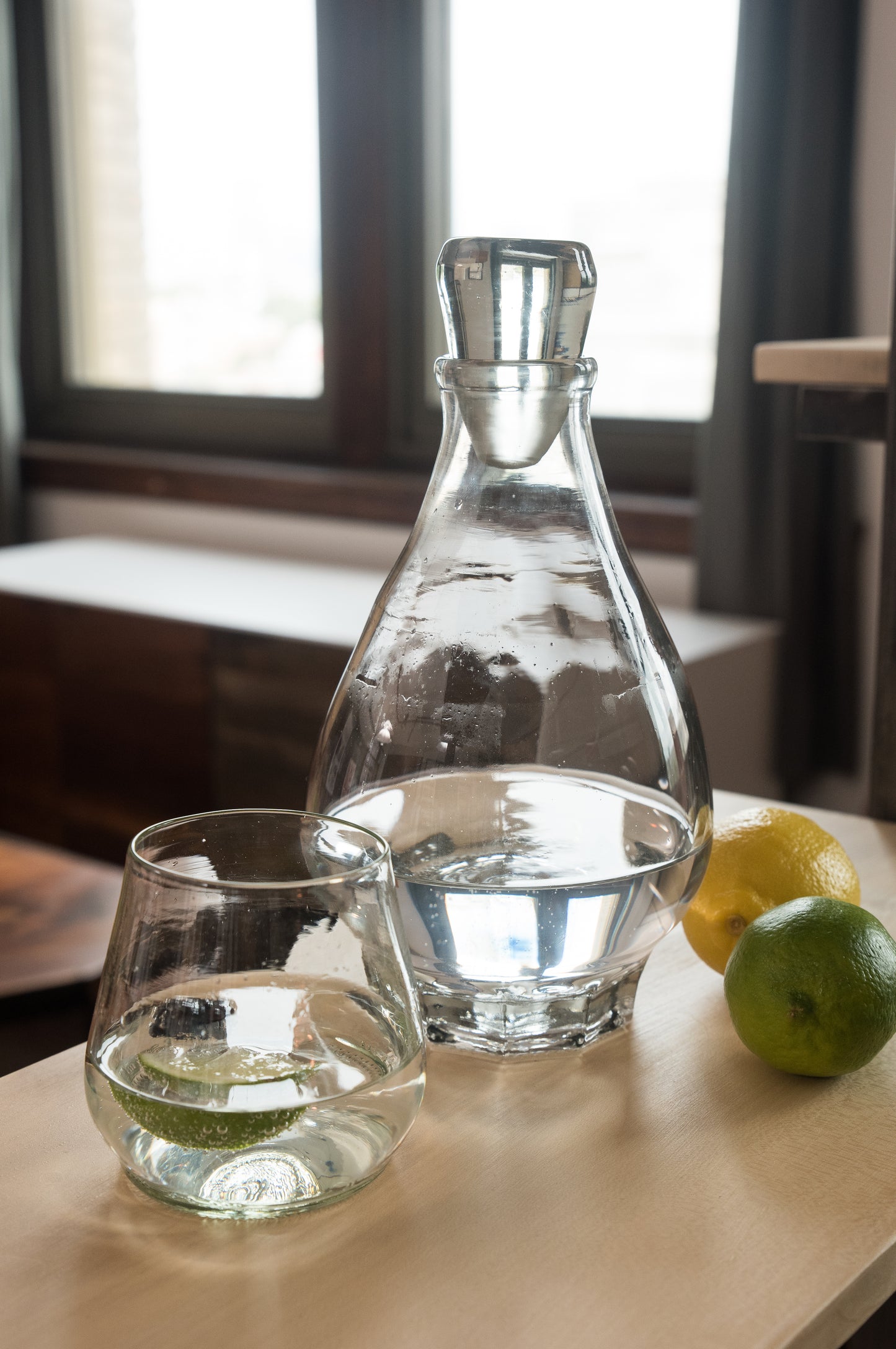 clear wine glass and decanter with sparking water and lime