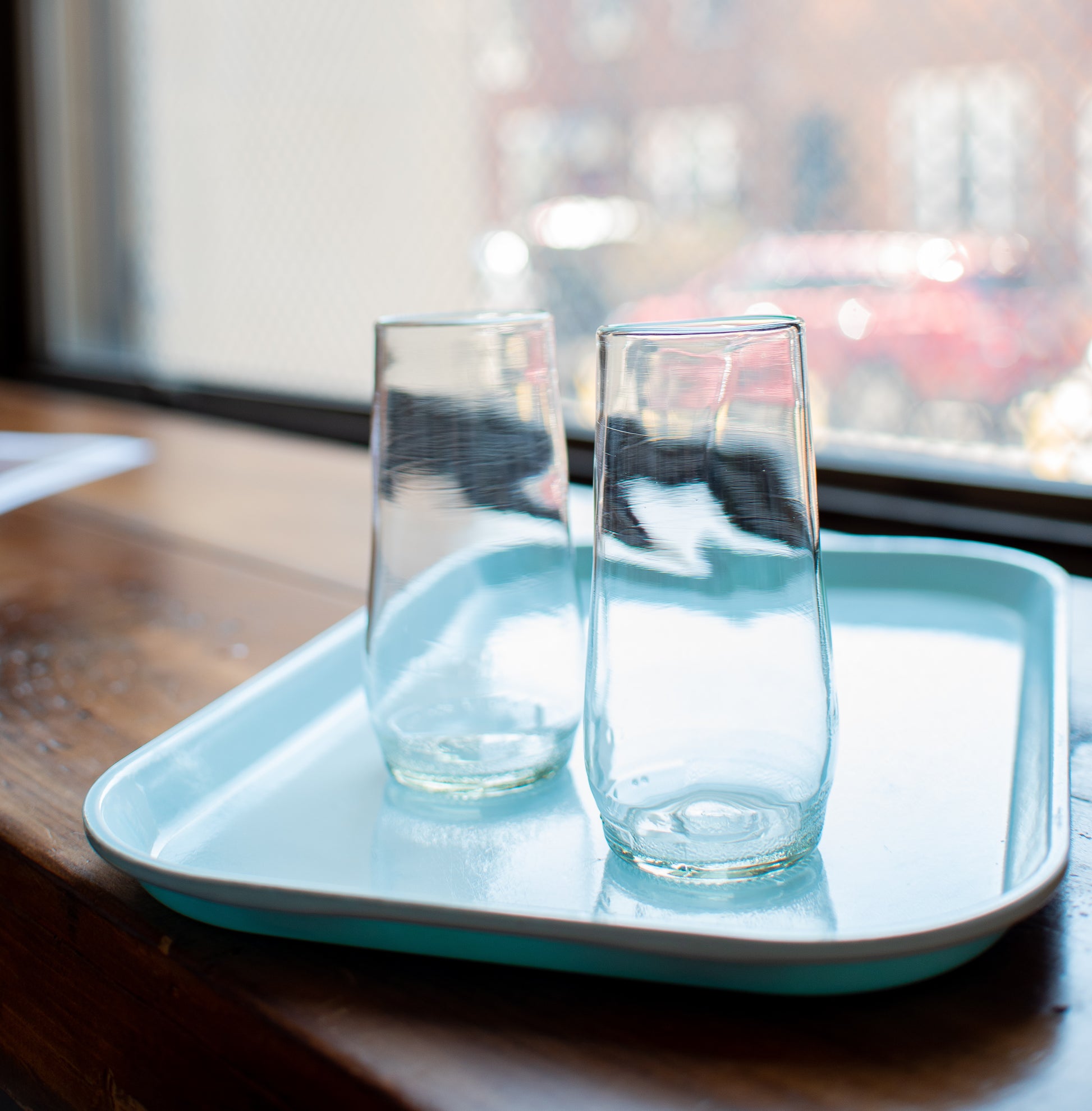 Clear flutes made from recycled glass on light blue tray